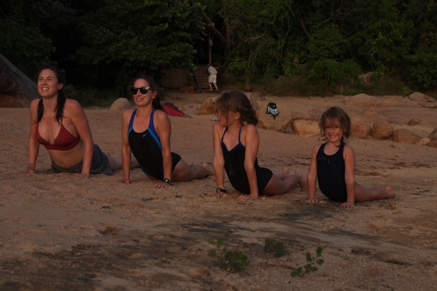 A family yoga group practicing together on the beach