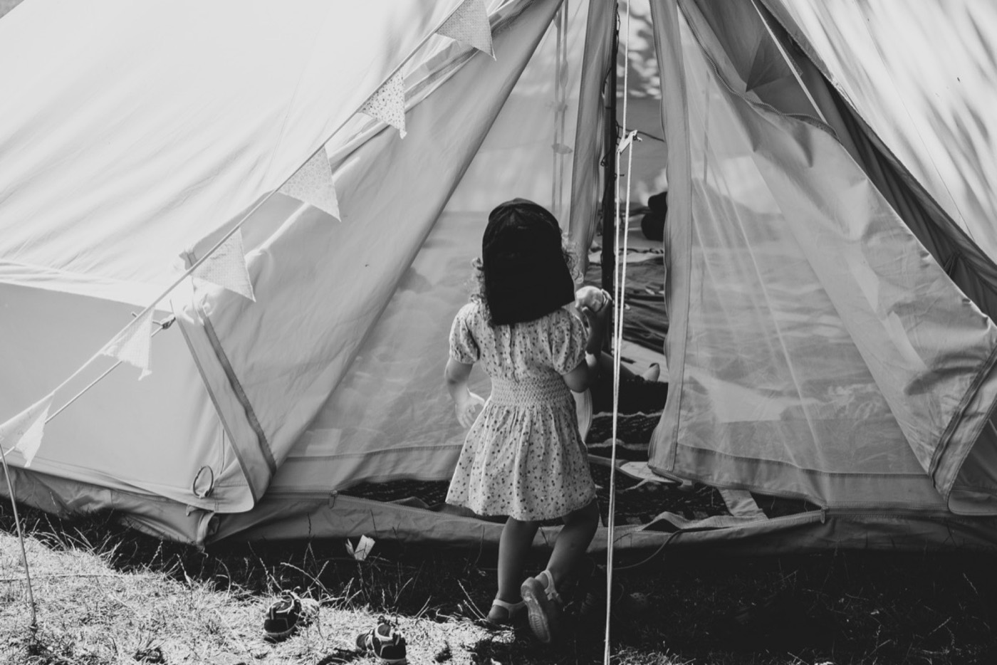 A child standing quietly near a tent outdoors
