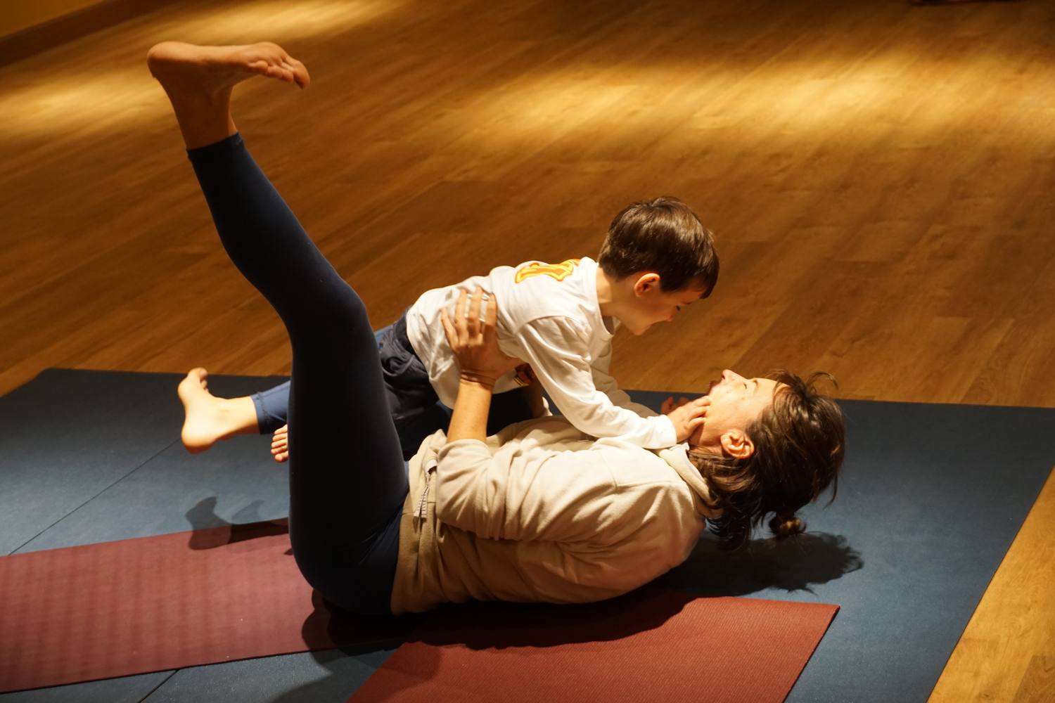 A parent and child balancing together in a playful parent-child yoga pose